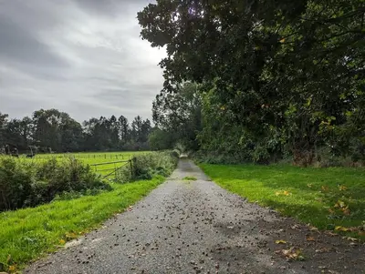 a gravel road in a field with a fence at Gaer Hall Guilsfield a country mansion with hottub in Welshpool