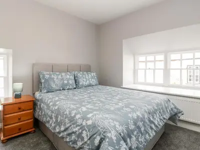 a bedroom with a bed and a nightstand and two windows at 19 Lion Street in Hereford