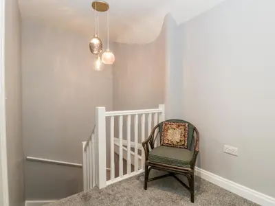 a room with a chair and stairs with a chandelier at 19 Lion Street in Hereford