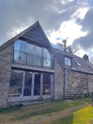 a stone house with large windows and a balcony at Hideaway in the Brecon Beacons in Brecon