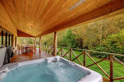 a hot tub on the deck of a house at Rhosllyn Retreats - Lakeside Lodge in Rhayader