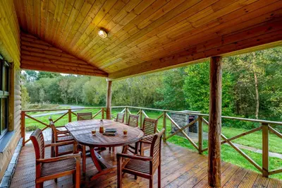 a wooden deck with a table and chairs on it at Rhosllyn Retreats - Lakeside Lodge in Rhayader