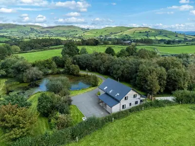 an aerial view of a white house in a field at Rhosllyn Retreats - Lakeside Lodge in Rhayader