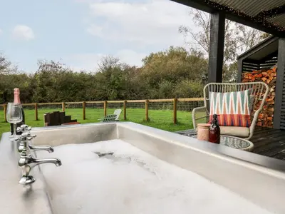 a bath tub filled with dirty water next to a patio at Dragonfly Shepherd's Hut in Aberaeron