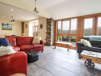 a living room with a red couch and a table at The Barn in Corwen
