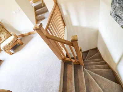 a winding staircase in a house with a wooden railing at The Barn in Corwen