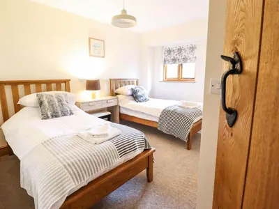 a small bedroom with two beds and a window at The Barn in Corwen