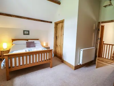 a bedroom with a large bed with a wooden frame at Hay Store in Corwen