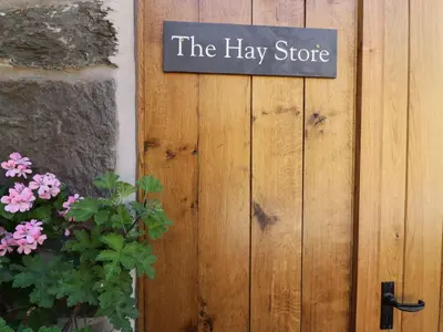 a sign that reads the hay store on a wooden door at Hay Store in Corwen