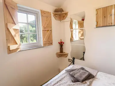a bedroom with a bed and a window at Chateau Petit in Caersws