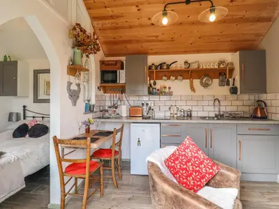a kitchen and living room with a table and chairs at Chateau Petit in Caersws