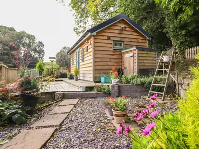 a garden with a tiny house in the background at Chateau Petit in Caersws