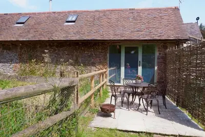 a table and chairs on the porch of a cottage at Nest Holiday Hideaway Dove Cottage-Beautiful Location in the Long Mynd Area of Outstanding Natural Beauty-WHIRLPOOL JACUZZI BATHS!! in Picklescott