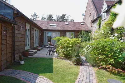 a patio with a table and chairs in a yard at Nest Holiday Hideaway Dove Cottage-Beautiful Location in the Long Mynd Area of Outstanding Natural Beauty-WHIRLPOOL JACUZZI BATHS!! in Picklescott