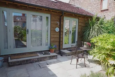 a patio with a table and chairs in front of a house at Nest Holiday Hideaway Dove Cottage-Beautiful Location in the Long Mynd Area of Outstanding Natural Beauty-WHIRLPOOL JACUZZI BATHS!! in Picklescott