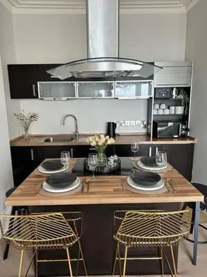 a kitchen with a wooden table with plates and glasses at Swn Y Mor 4 Aberystwyth in Aberystwyth