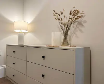 a white dresser with a lamp and a vase of flowers on it at Swn Y Mor 4 Aberystwyth in Aberystwyth