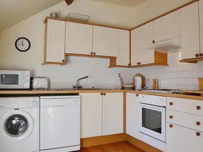 a kitchen with white cabinets and a washer and dryer at Granary Cottage in Oswestry