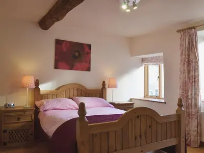 a bedroom with a wooden bed with pink pillows at Granary Cottage in Oswestry