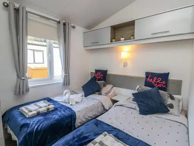 a living room with two beds and a window at 95 Hafan Taffy in Llanina