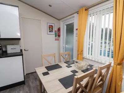 a kitchen and dining room with a table and chairs at 95 Hafan Taffy in Llanina