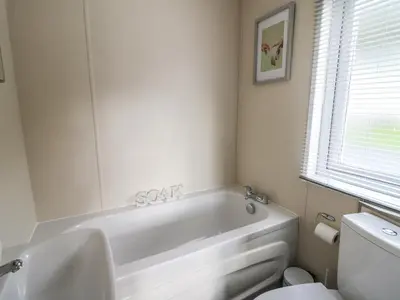 a bathroom with a white tub and a toilet at 95 Hafan Taffy in Llanina