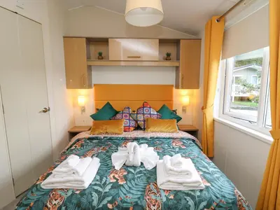 a caravan bedroom with a bed with towels on it at 95 Hafan Taffy in Llanina