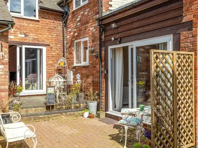 a brick house with a patio with a table and chairs at The Coach House- Uk45660 in Bishops Castle