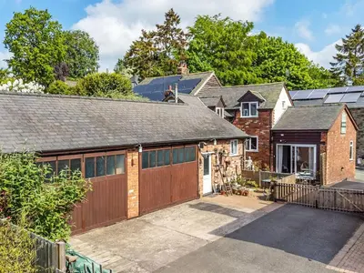 a brick house with a garage and a driveway at The Grooms Cottage-Uk45659 in Bishops Castle