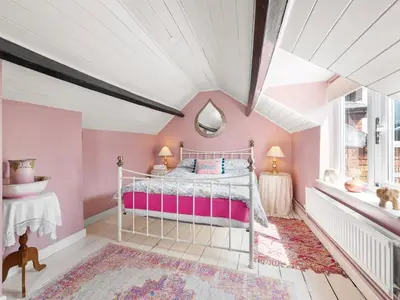 a bedroom with pink walls and a white ceiling at The Grooms Cottage-Uk45659 in Bishops Castle