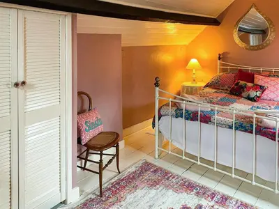 a bedroom with a bed and a chair and a mirror at The Grooms Cottage-Uk45659 in Bishops Castle
