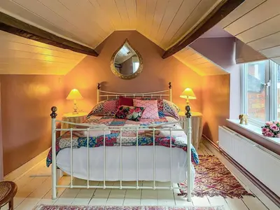 a bedroom with a bed with a mirror and a window at The Grooms Cottage-Uk45659 in Bishops Castle