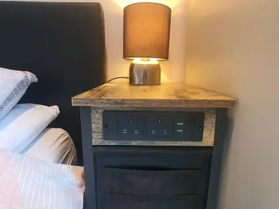 a lamp on a night stand next to a bed at Idyllic 2 Bedroom Self-Contained UpsideDown Annexe in Llandrindod Wells