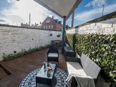 a patio with a table and chairs and a brick wall at Modern flat a short walk from Shrewsbury centre - Pass the Keys in Shrewsbury