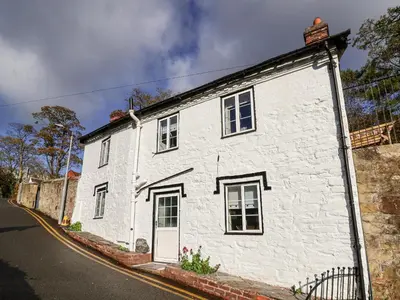 a white brick building with a door on a street at Wharf Cottage in Llangollen