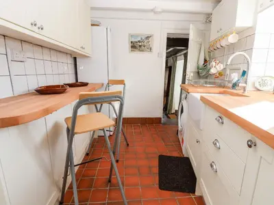 a kitchen with white cabinets and a red tile floor at Wharf Cottage in Llangollen
