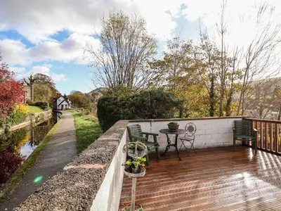a patio with a table and chairs on a wooden deck at Wharf Cottage in Llangollen
