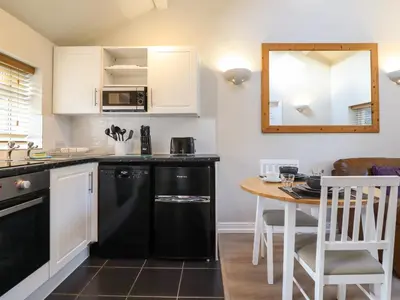 a kitchen with a table and a black dishwasher at Tan Isa in Harlech