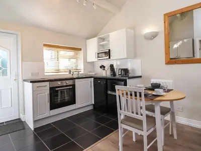 a kitchen with white cabinets and a wooden table at Tan Isa in Harlech