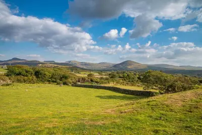 a green field with mountains in the background at Melin-Byrdir in Dyffryn