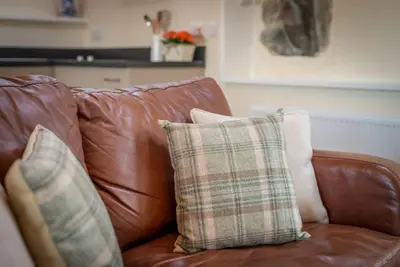 a brown leather couch with two pillows on it at Stabal-Byrdir in Dyffryn