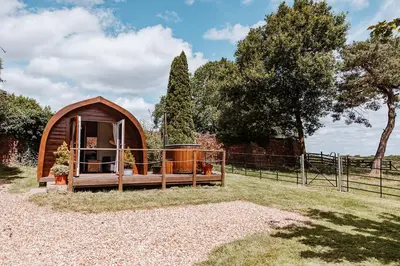 a small tent in a field with a fence at Secluded Cosy Luxury Pod with wood fired hot tub in Shrewsbury