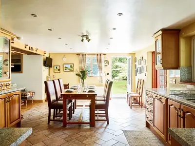 a kitchen with a wooden table and chairs and a dining room at Bedlwyncoch Farmhouse in Brecon