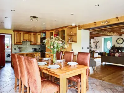 a kitchen and dining room with a wooden table and chairs at Bedlwyncoch Farmhouse in Brecon
