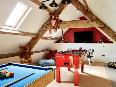 a attic room with a pool table and a tv at Bedlwyncoch Farmhouse in Brecon