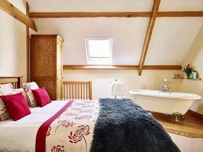 a bedroom with a bed and a tub and a sink at Trefaen Cottage in Brecon