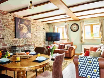 a living room with a table and a stone wall at Llysfaen Cottage in Brecon