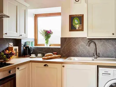 a kitchen with white cabinets and a sink and a window at Llysfaen Cottage in Brecon