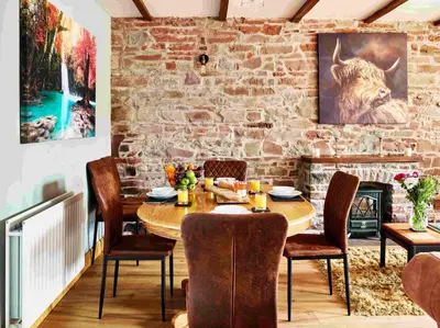 a dining room with a table and chairs and a fireplace at Llysfaen Cottage in Brecon