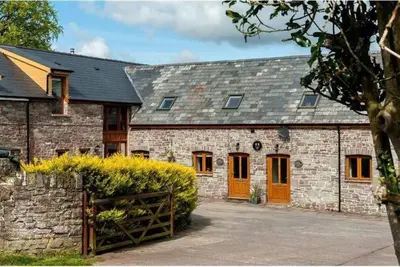 a brick building with orange doors and a fence at Llysfaen Cottage in Brecon
